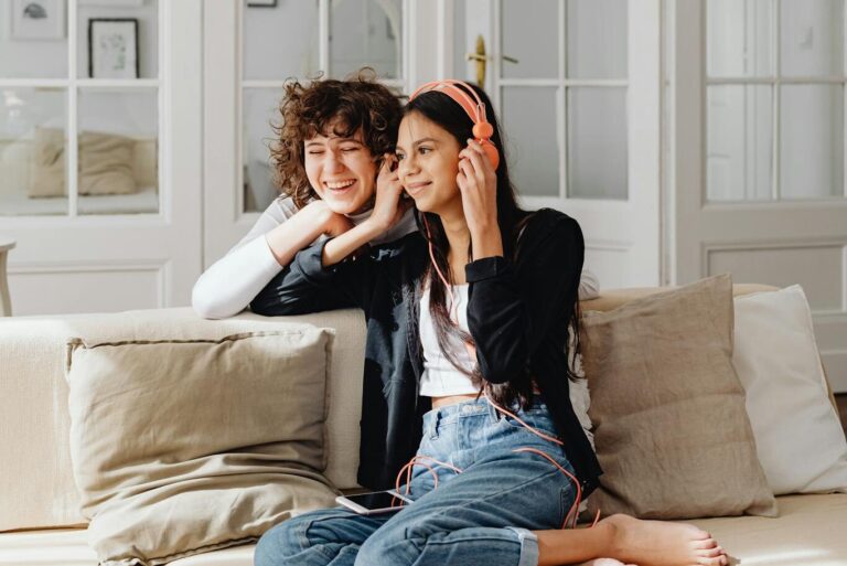 Women Sitting on a Sofa Listening to Music